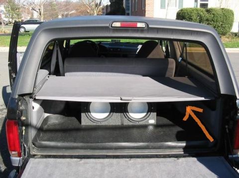 1996 Ford Bronco - The rear cargo area of a 1996 Ford Bronco is visible, a subwoofer box and a retracted cargo cover.