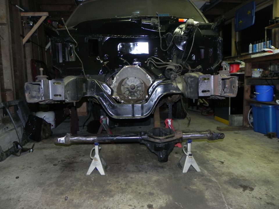 Vehicle frame on jack stands, engine exposed, front differential removed