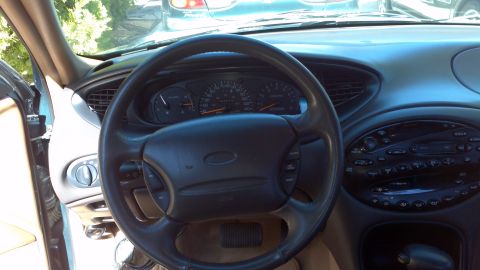 1996 Ford Taurus - The dashboard of a 1996 Ford Taurus features a prominent steering wheel and instrument cluster.