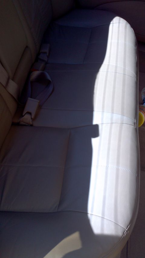 1996 Ford Taurus - The interior of a car shows the rear seats and seatbelts, with a strong light source creating a shadow.