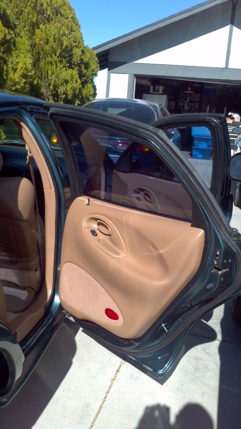 1996 Ford Taurus - The interior of a green sedan is shown with both front and rear doors open, revealing tan upholstery.