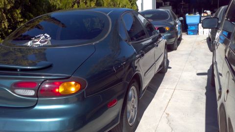 1996 Ford Taurus - The rear quarter panel and taillight assembly of a dark green sedan are visible.