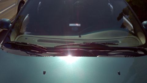 1996 Ford Taurus - Front view of a teal car's hood and windshield, with significant sun glare obscuring details.