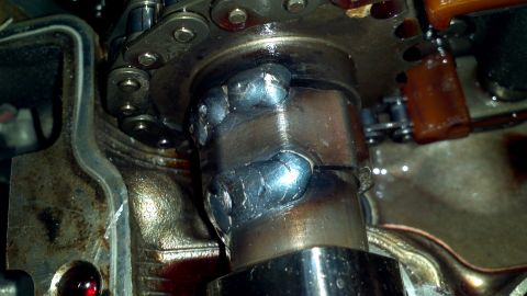 1996 Ford Taurus - Camshaft lobe shows evidence of welding, with timing chain and engine components in the background.