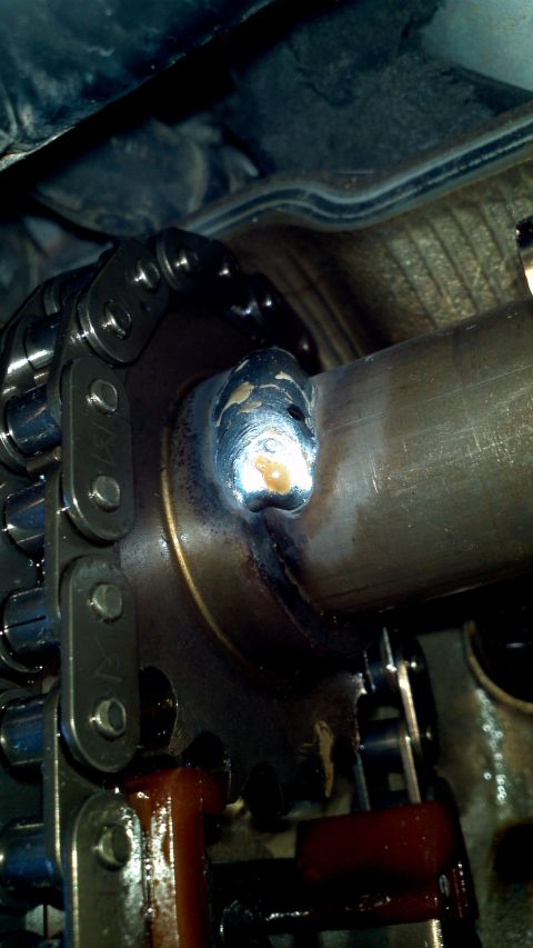 1996 Ford Taurus - Close-up view of a timing chain mechanism connected to a welded pipe, with visible oil residue.