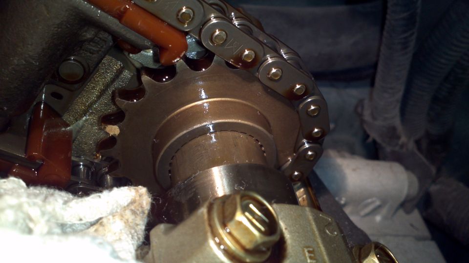 close-up of engine timing chain and sprocket with oil