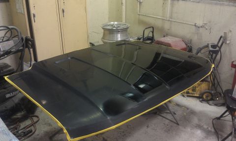 1995 Ford Bronco - A black car hood is taped and ready for work in a garage setting.