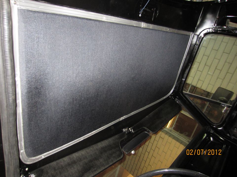 Interior shot of a vehicle's door panel and window frame, showing black textured material and chrome trim