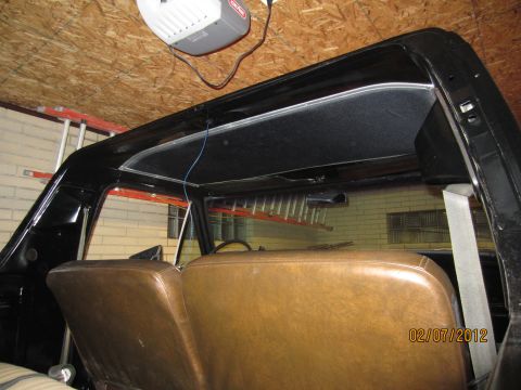 1979 Ford Bronco - Interior view of the rear of a classic vehicle, likely a 1979 Ford Bronco, showing brown leather seats and the black headliner and roof fra…