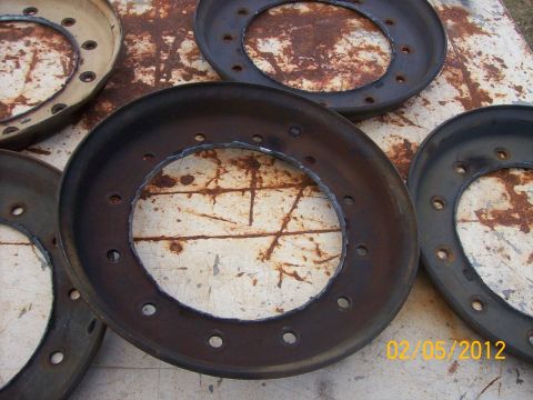 1982 Ford F-100 - Multiple rusty metal rings with bolt holes are laid out on a weathered surface.