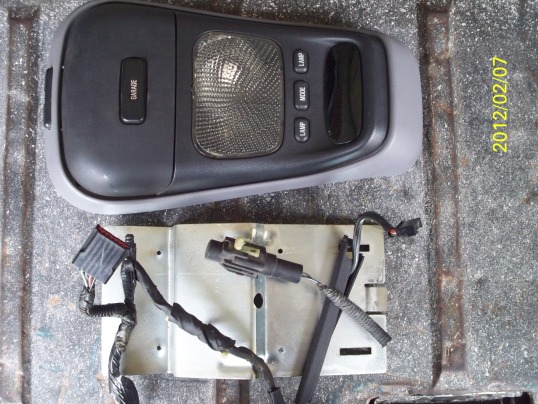 Overhead console with buttons labeled GARAGE, LAMP, MODE, and LAMP, next to a metal bracket with wiring