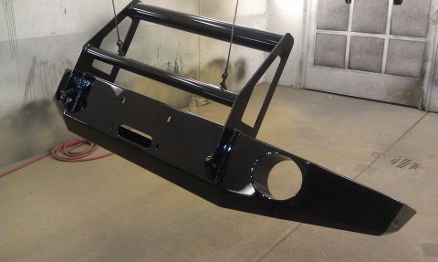 1995 Ford Bronco - Black bull bar with winch mount, suspended for painting, with a red hose coiled on the floor.