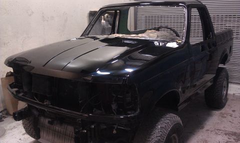 1995 Ford Bronco - This 1995 Ford Bronco is in a workshop, missing its grille and headlights, indicating ongoing repair work.