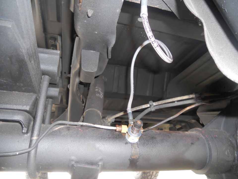 Close-up of a brake line fitting on the rear axle of a vehicle