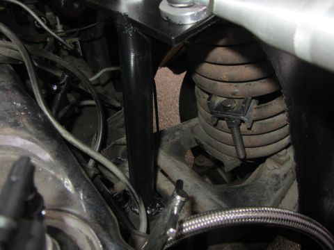 1964 Ford Ranchero - Close-up view of engine bay bracing and suspension components, showing a black metal brace and a coil spring.