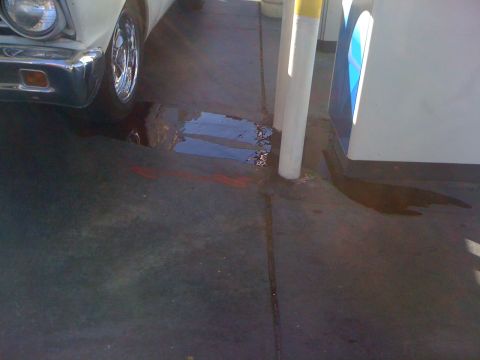 1964 Ford Ranchero - A vehicle is parked on pavement, with a noticeable puddle of fluid beneath it.