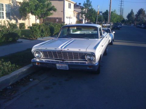 1964 Ford Ranchero - A white 1964 Ford Ranchero is parked on a residential street, showing its front grille and California license plate.