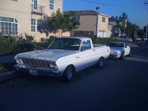 1964 Ford Ranchero - A white 1964 Ford Ranchero is parked on a street next to a white convertible.