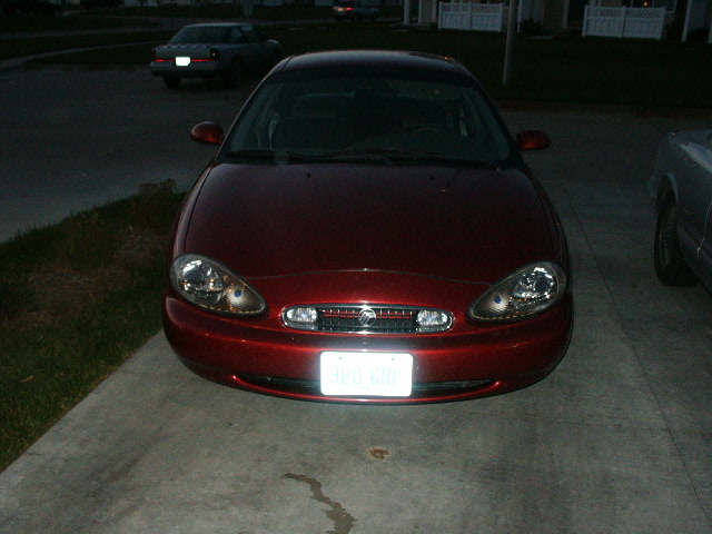 Red 1998 Mercury Sable sedan parked in driveway, front view, with a second car in the background