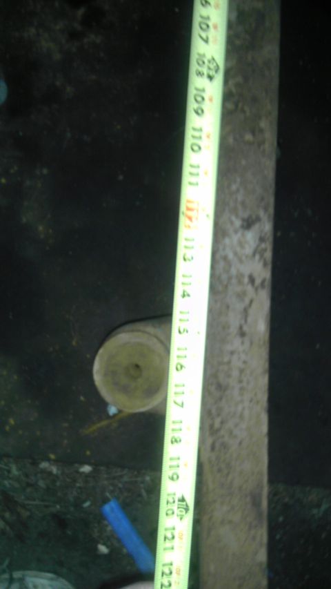 1987 Ford Ranger - A tape measure is used to measure the length of a cylindrical object next to a weathered wooden post.