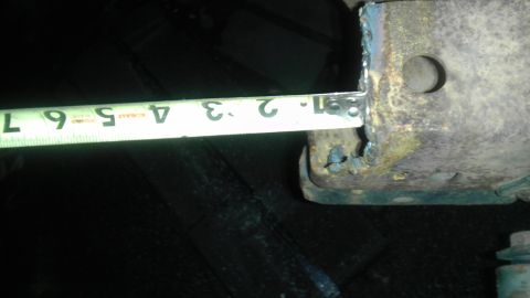 1987 Ford Ranger - A measuring tape is used to measure a rusty metal component, likely part of a vehicle's suspension system.
