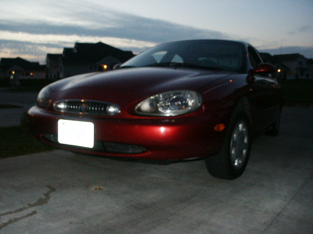 Red sedan parked on concrete driveway at dusk