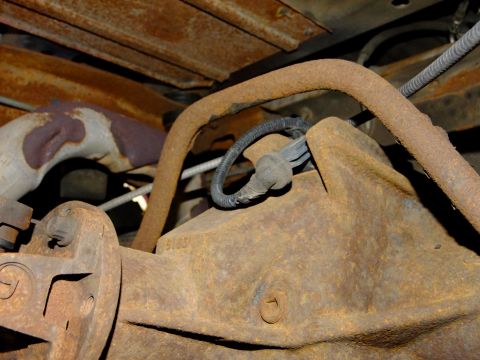 1995 Ford Bronco - The underside of a vehicle shows a heavily rusted rear differential and exhaust system components.