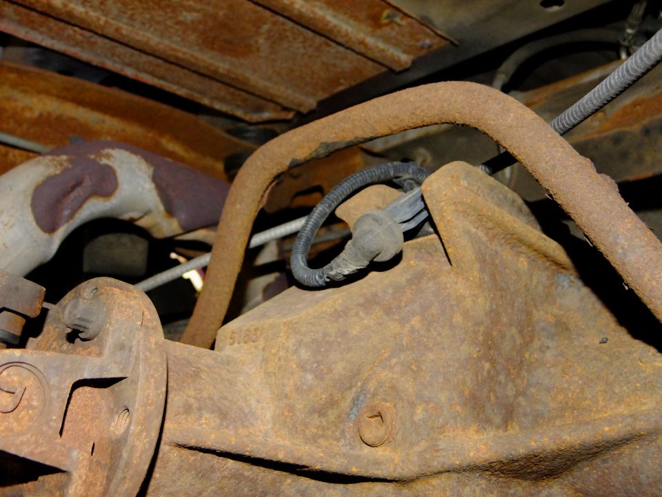 close-up of rusty rear differential and exhaust pipe on a vehicle
