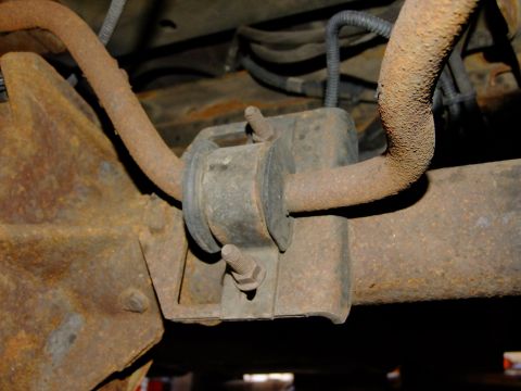 1995 Ford Bronco - Close-up of a heavily rusted suspension component on a vehicle's rear axle.