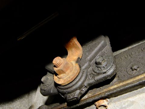 1995 Ford Bronco - Close-up view of a rusted metal bracket with a bolt and nut, likely part of a vehicle's chassis.