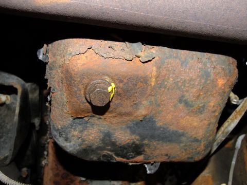 1995 Ford Bronco - The underside of a vehicle shows significant rust on the oil pan and surrounding components.