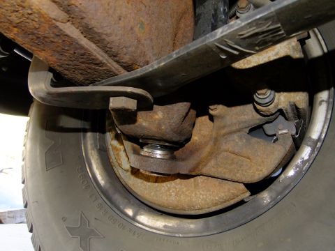 1995 Ford Bronco - Rusty rear suspension leaf spring and brake drum assembly, likely from an older vehicle.