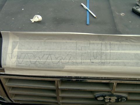 1982 Ford Bronco - Close-up of a vehicle's grille with a template for lettering applied over it.
