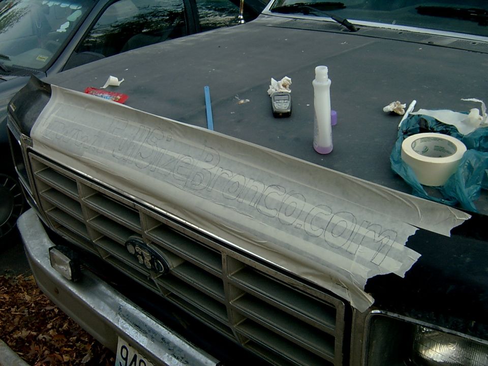 Pencil-traced FullSizeBronco.com paper stencil taped to Ford hood above bar grille