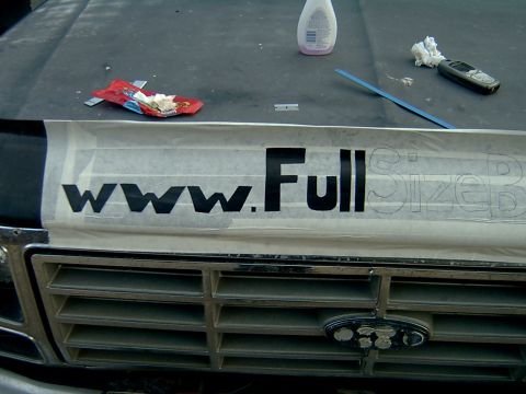 1982 Ford Bronco - Applying vinyl lettering to the hood of a truck over the grille.