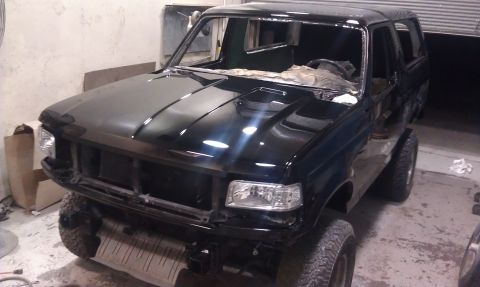 1995 Ford Bronco - This black Ford Bronco, likely from the early to mid-1990s, is in a workshop with its windshield removed.