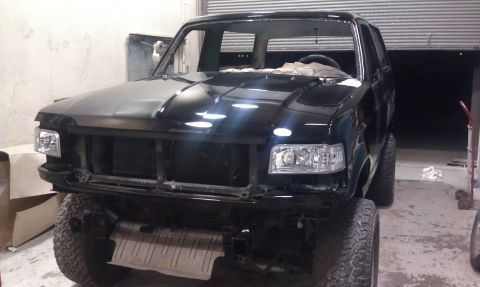 1995 Ford Bronco - This 1995 Ford Bronco is in a garage, appearing to be in the process of restoration or repair, with its front grille missing.