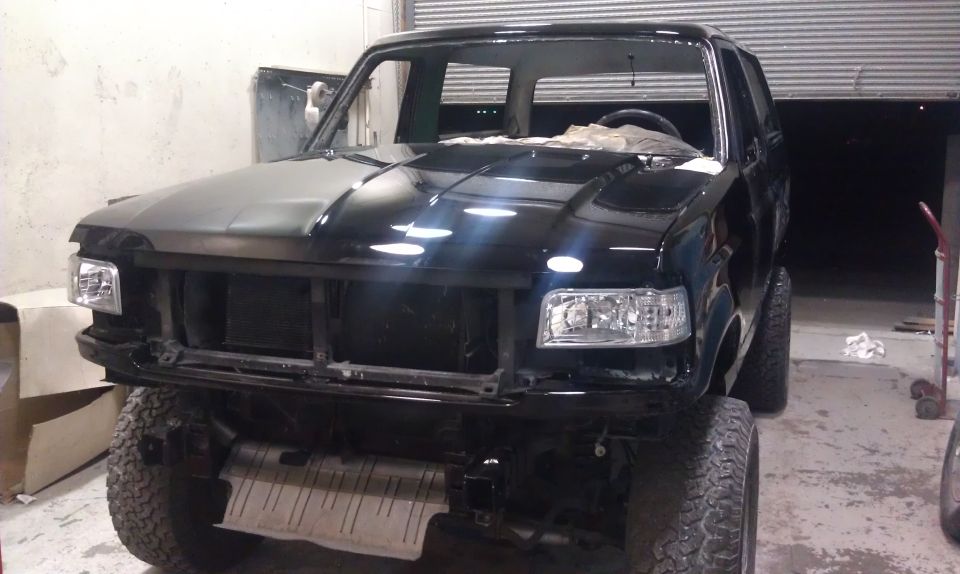 Black 1995 Ford Bronco front end with grille removed, undergoing repairs