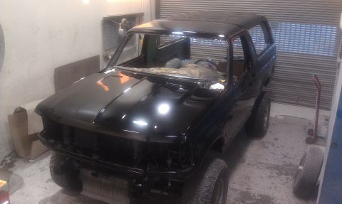 1995 Ford Bronco - A black 1995 Ford Bronco is seen in a garage, appearing to be in the process of restoration or repair.