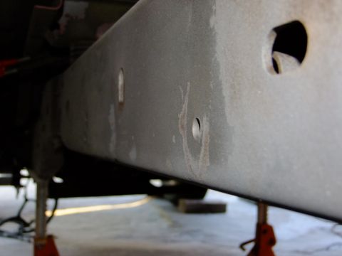1995 Ford Bronco - The underside of a vehicle's frame rail is shown, supported by jack stands.