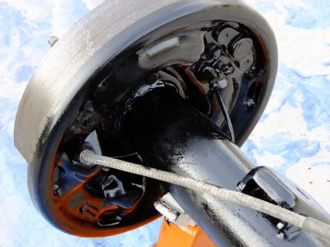 1995 Ford Bronco - Close-up view of a freshly detailed rear axle and brake drum assembly, showing the intricate mechanical components and a braided metal cabl…