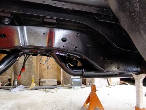1995 Ford Bronco - The underside of a vehicle's chassis has been freshly painted and is supported by jack stands in a workshop.