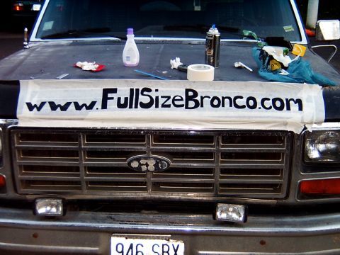 1982 Ford Bronco - The grille and front end of a Ford Bronco, with a website banner and various items on the hood.