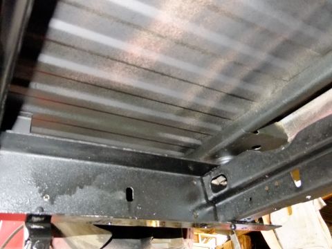 1995 Ford Bronco - Close-up view of the underside of a vehicle's chassis, showing the ribbed metal bed and black frame components.