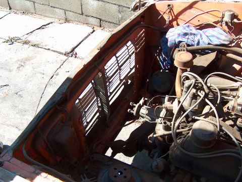 1960 Ford Ranchero - The engine bay of an orange vehicle shows various engine parts and a cloth draped over some components.