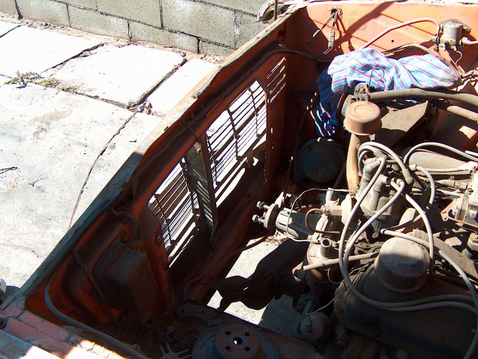 Engine bay of an orange vehicle with visible engine components and a cloth covering
