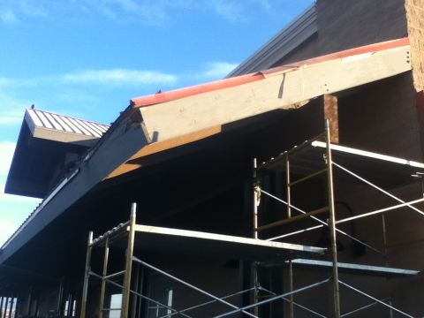 2006 Ford E350 - Scaffolding is erected around a building with a damaged overhang, revealing exposed structural elements.