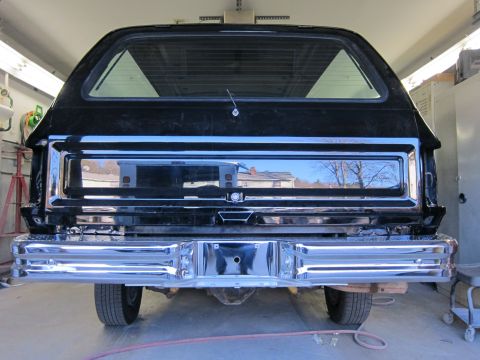 1987 Dodge 1500 - Rear view of a black pickup truck, likely from the 1980s, showing its chrome bumper and tailgate area.