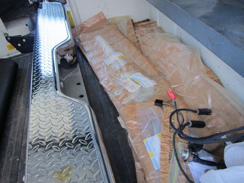 1987 Dodge 1500 - Wrapped parts and wiring harnesses are stored in the bed of a truck next to diamond plate trim.