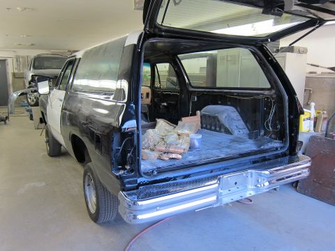 1987 Dodge 1500 - The rear of a Dodge Ramcharger is shown with its tailgate open, revealing the cargo area. Another vehicle is parked behind it.